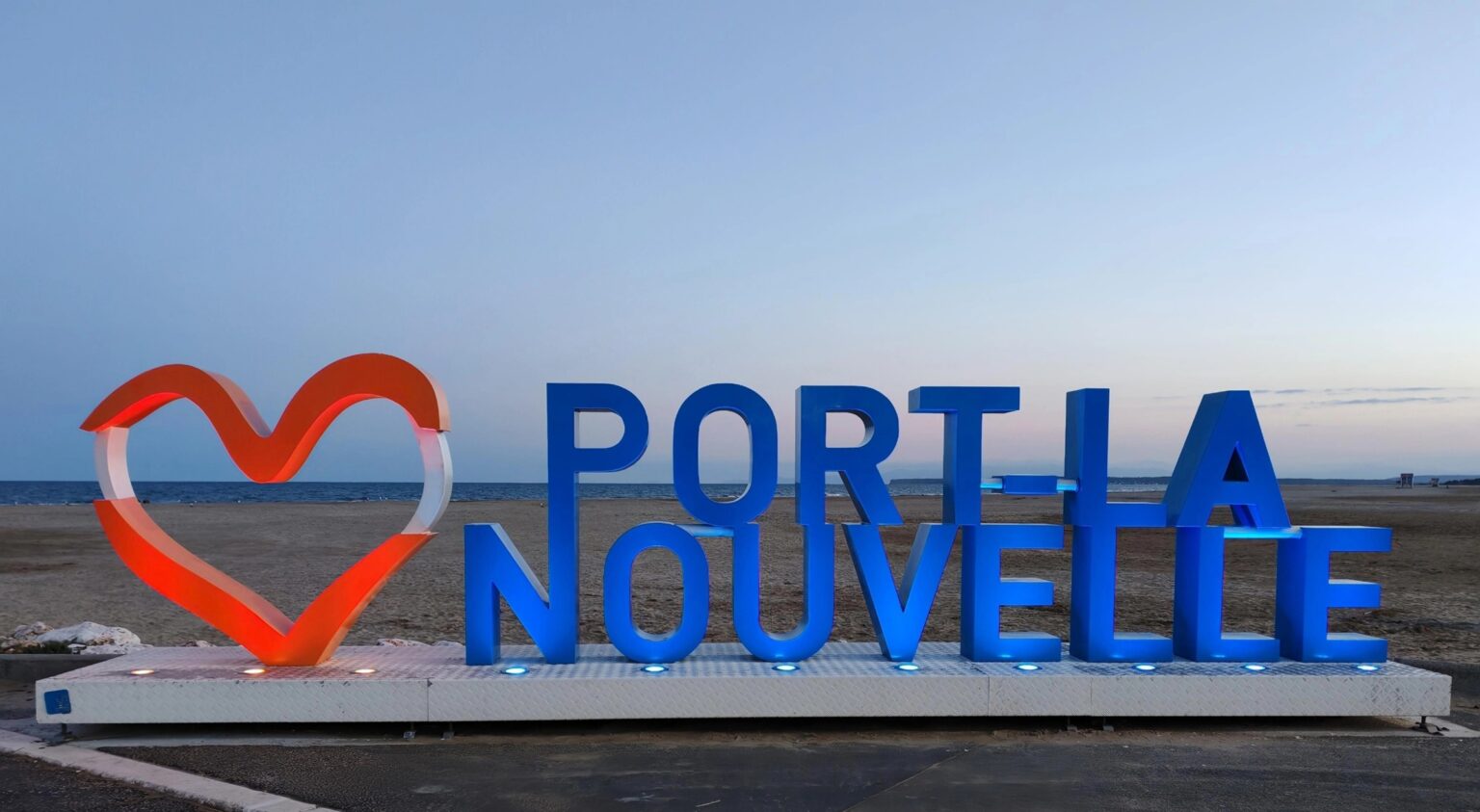 Schriftzug Port-la-Nouvelle mit rotem Herz am Strand in der Abenddämmerung
