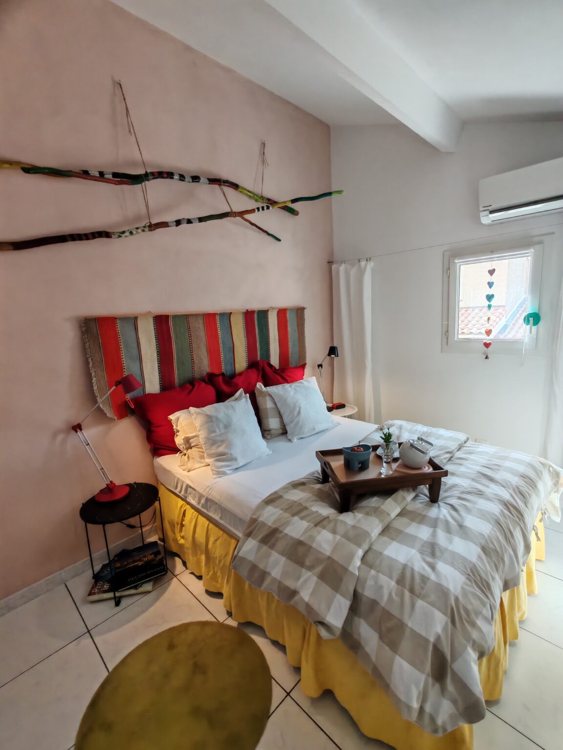 Schlafzimmer mit Doppelbett, karierter Tagesdecke und rotem Kopfteil